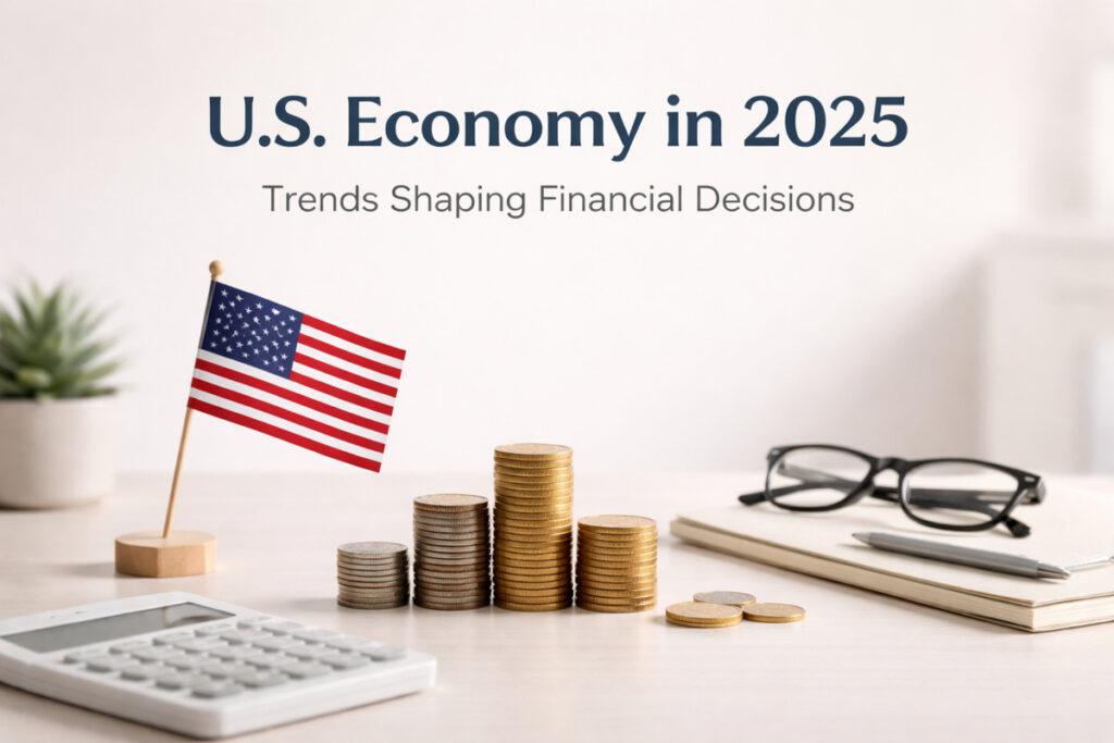 Banner reading ‘U.S. Economy in 2025’ and ‘Trends Shaping Financial Decisions’ above a desk scene with a small U.S. flag on a stand, stacked coins of varying heights, a calculator, a notebook with a pen, and eyeglasses; a blurred plant sits in the background, suggesting finance and economic planning.